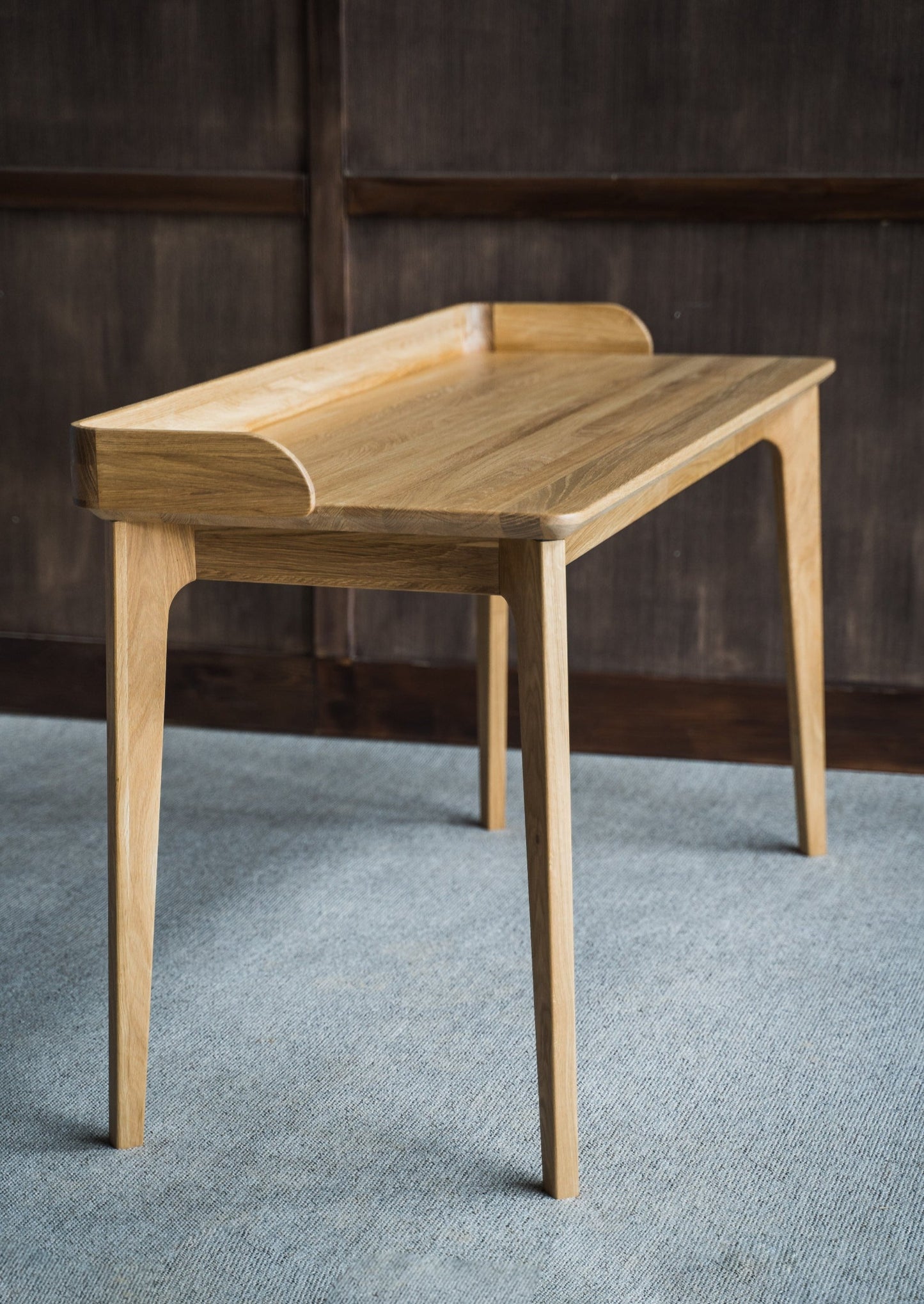 Skrivebordet Orion skiller seg ut med sin naturlige, tidløse og elegante design. Håndlaget skrivebordet i massiv eik med sin naturlige bordplate bringer frem treverkets karakter.